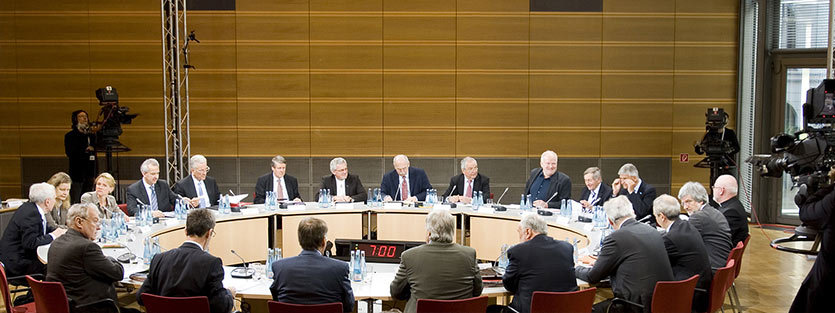 A discussion facility is set up at a round table where 20 women and men sit and confer