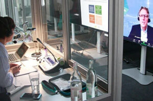 View of an interpreting studio, where female interpreters follow a speaker on a large monitor and translate him into various other languages in their soundproof booths