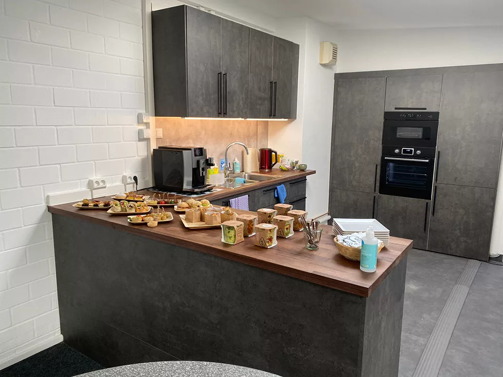 A functional kitchen from PCS; a buffet is laid out on the L-shaped counter for interpreters. The catering is predominantly vegetarian and vegan.