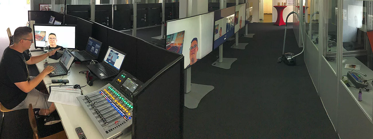 In a room called the interpreting hub, there are lots of interpreting booths and monitors in front of these booths. You can also see a technical control room with various mixing consoles and laptops, where a technician sits and prepares the technical aspects of an upcoming conference.